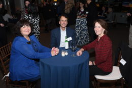 two women and a man seated at table smiling for photo