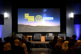 empty stage with four chairs with large screen in background with the rochester effect graphic