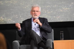 man in glasses speaking as he sits on stage