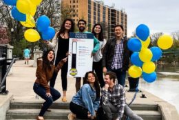 group of students on stairs posing for photo with balloons