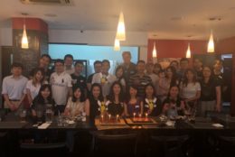 large group posing for photo with rocky cutouts and birthday cake and candles