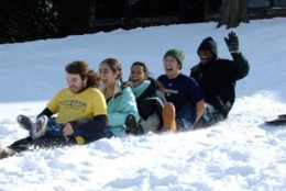 five students sledding down snowy hill