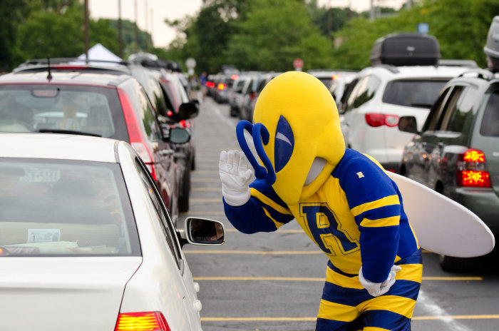 UR mascot Rocky greets incoming freshmen in park lot during move-in day at University of Rochester's River Campus