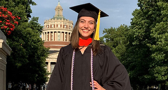 Amanda Tatem ’20 wearing cap and gown in front of rush rhees library quad