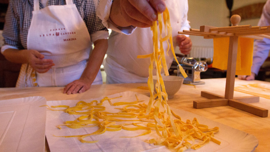 Pasta noodles on a counter with hands picking it up