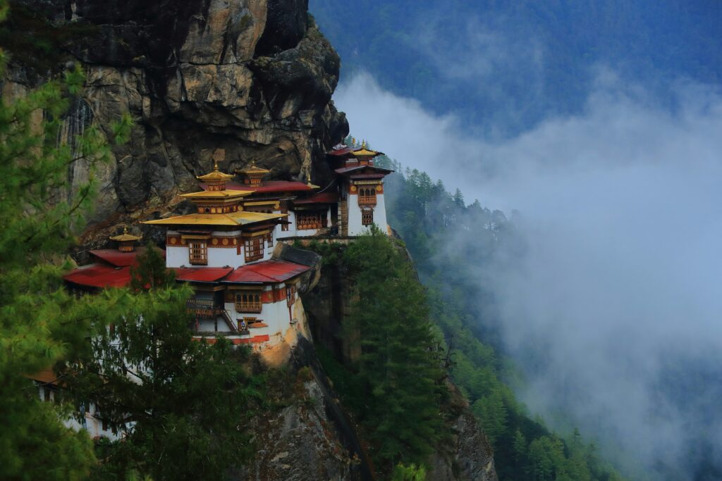 Temples against a cliff side, with mist in the background