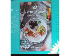 A promotional image for Tastefully Simple’s 30th anniversary featuring a plate of appetizers, a bottle of Bayou rum, and text that reads “Effortless Flavor. Endless Inspiration.” along with the website tastefullysimple.com.