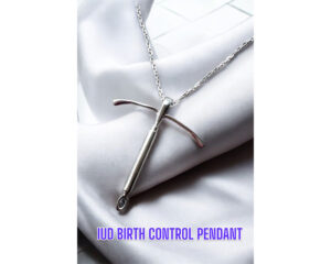 A close-up image of a silver necklace featuring a pendant shaped like an intrauterine device (IUD), displayed on a white satin fabric background with the text “IUD Birth Control Pendant” below.