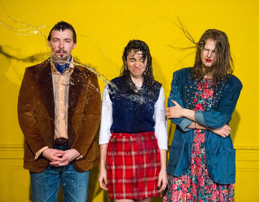 three student actors getting water thrown on them
