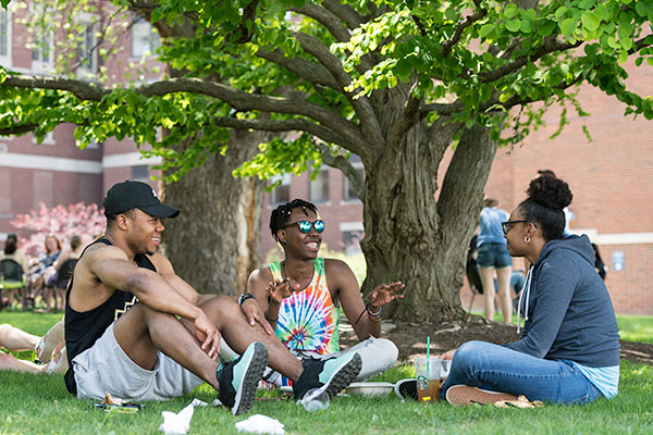 Three students sitting outside and laughing.