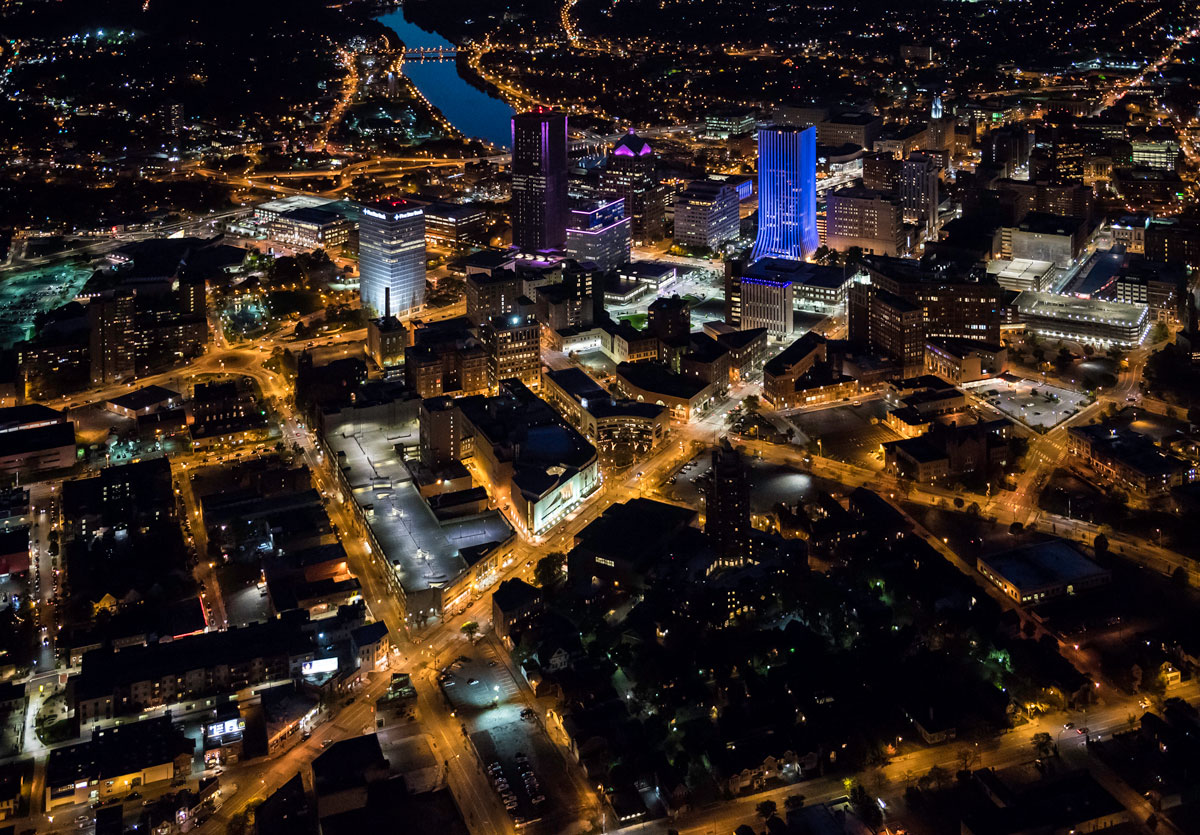 Aerial view of Rochester, New York, illuminated at night, showcasing city lights and urban layout.
