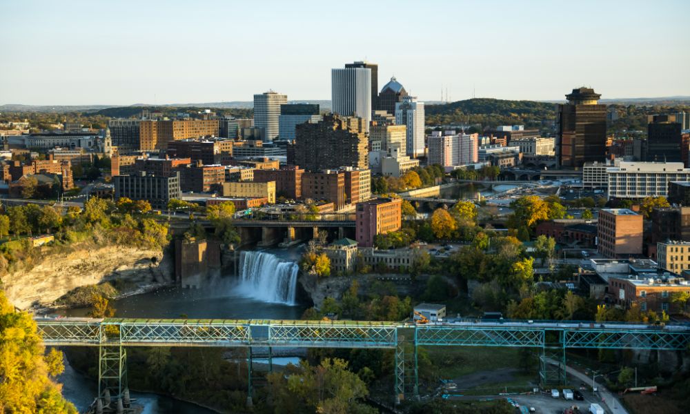 A panoramic view of Rochester from a hilltop, showcasing the skyline and urban landscape, with the University of Rochester nearby.