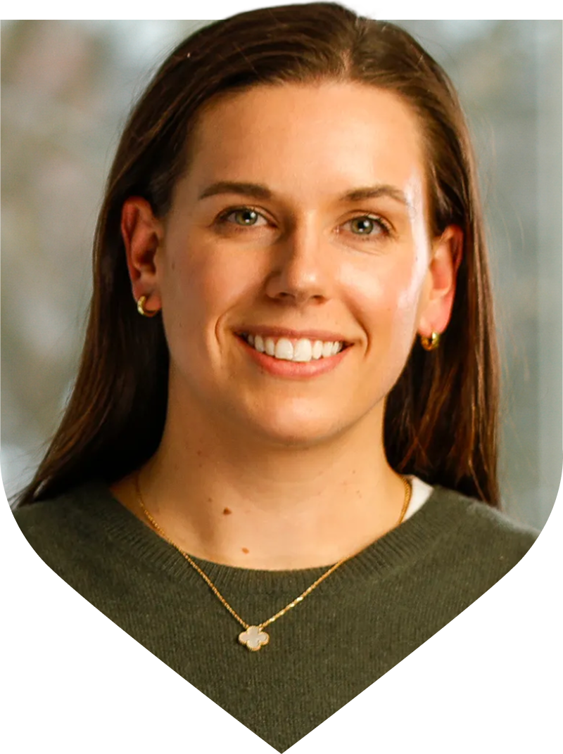 A woman with long hair in a green sweater, identified as University of Rochester alum Farrell Cooke.
