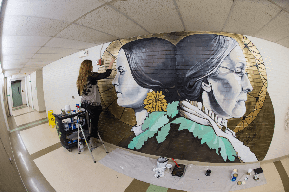 Artist painting a mural at University of Rochester