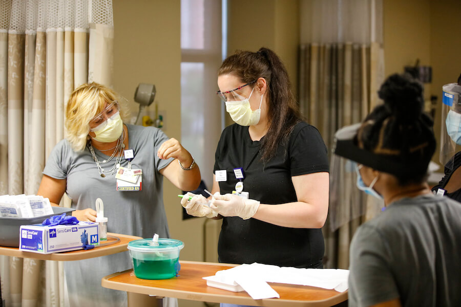 A University of Rochester School of Nursing student is being taught how to handle medical equipment in a hospital setting.