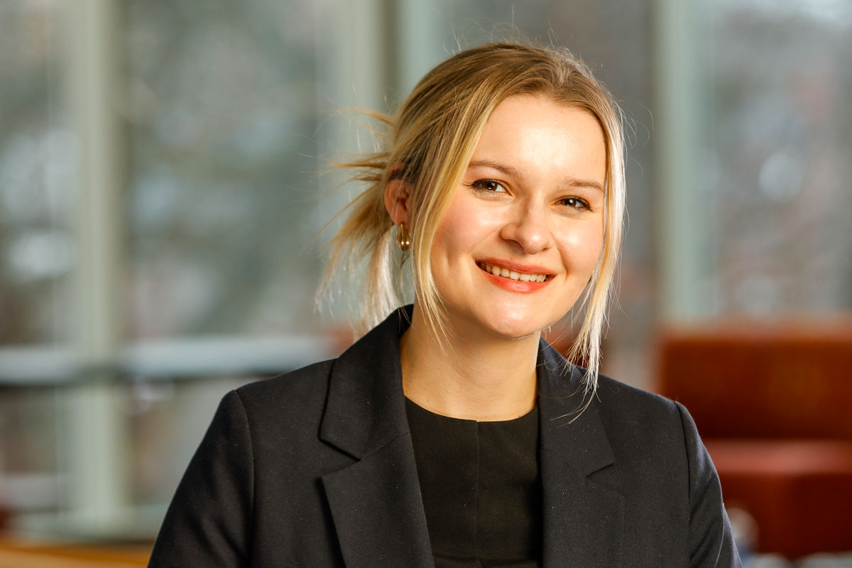A smiling woman in a suit and tie, representing University of Rochester Alumni, Lea Thome ’22.