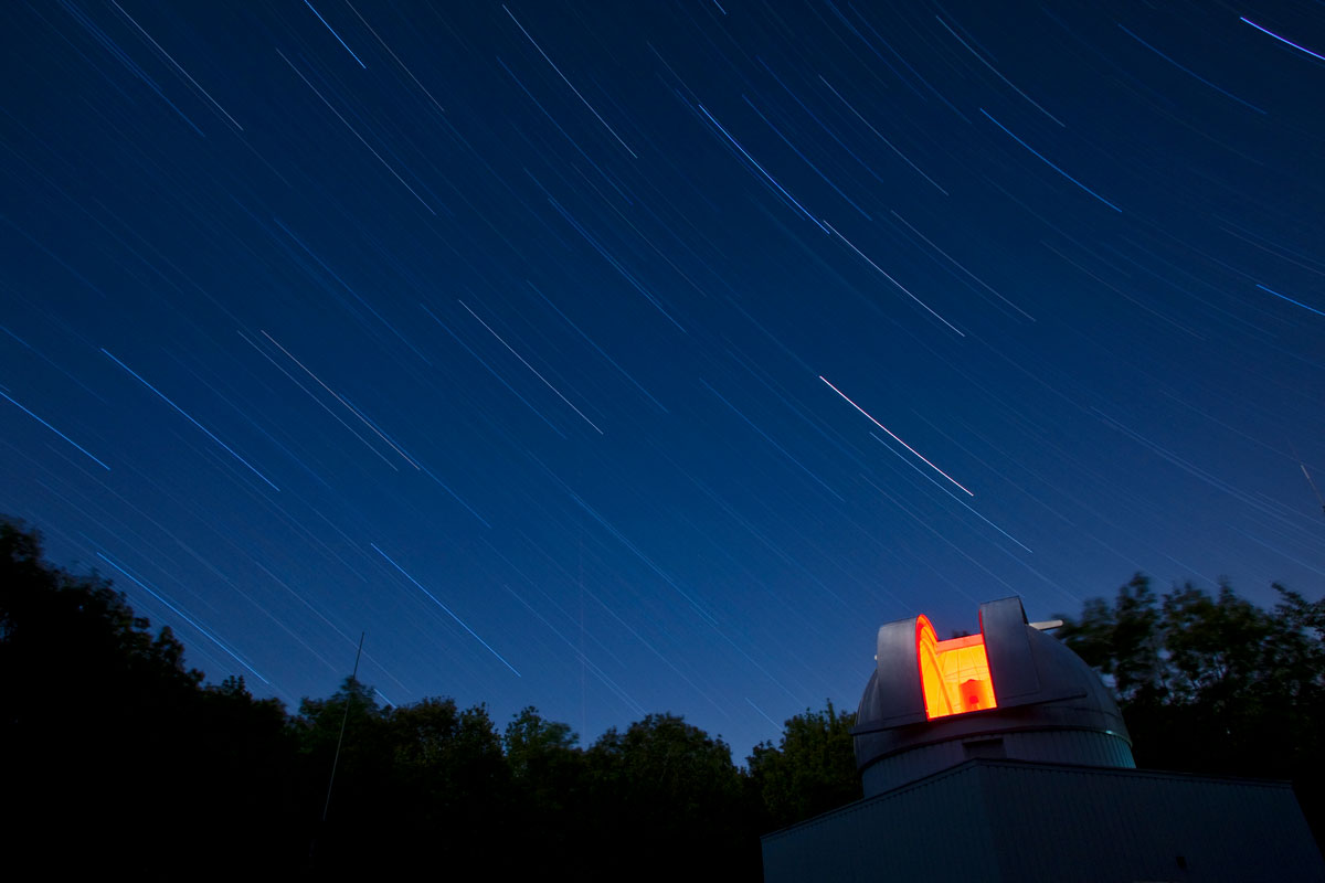 Star trails illuminate the night sky above the University of Rochester observatory, showcasing celestial movement and research.