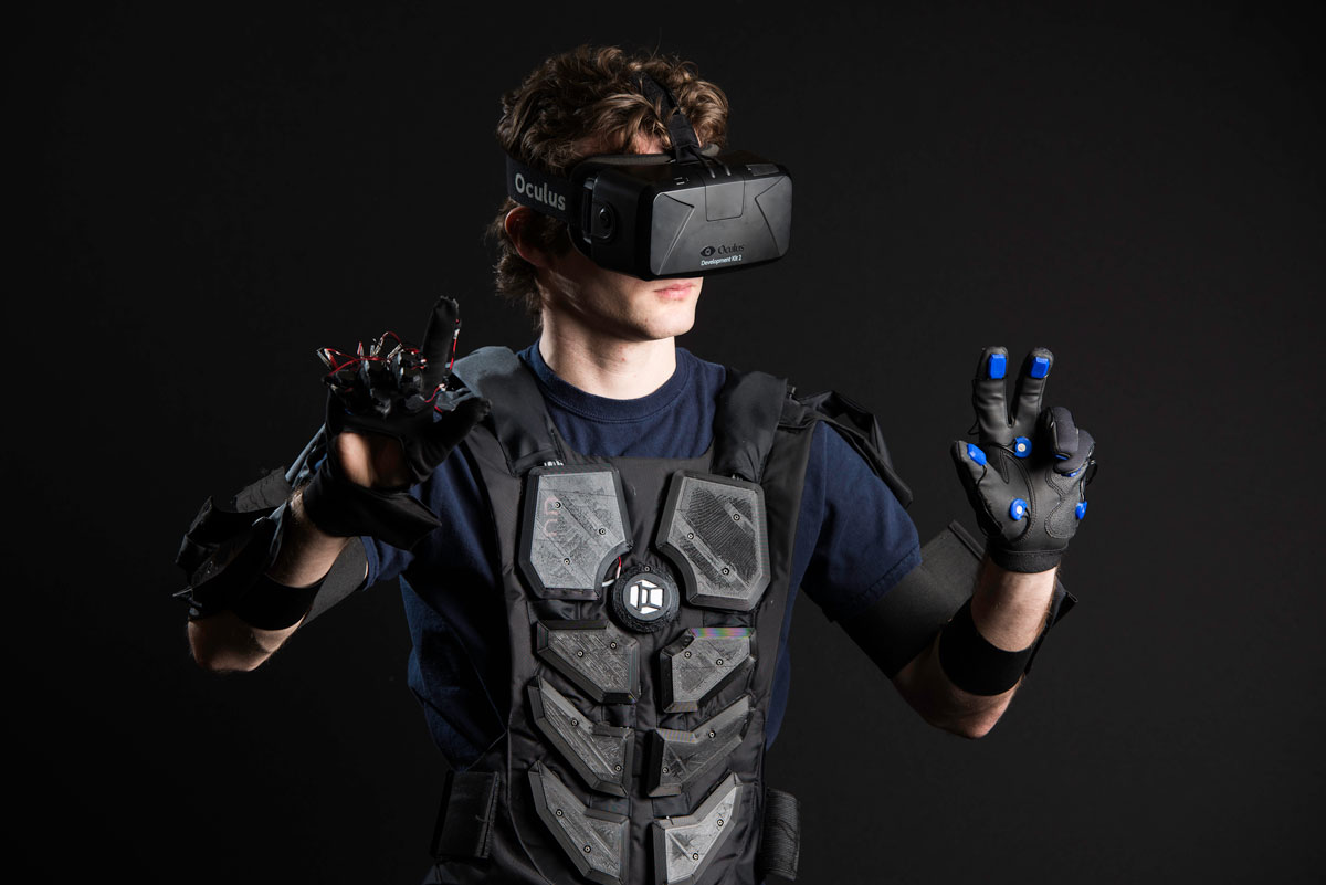 A man at the University of Rochester engages with virtual reality, wearing a headset and gloves for an immersive experience.