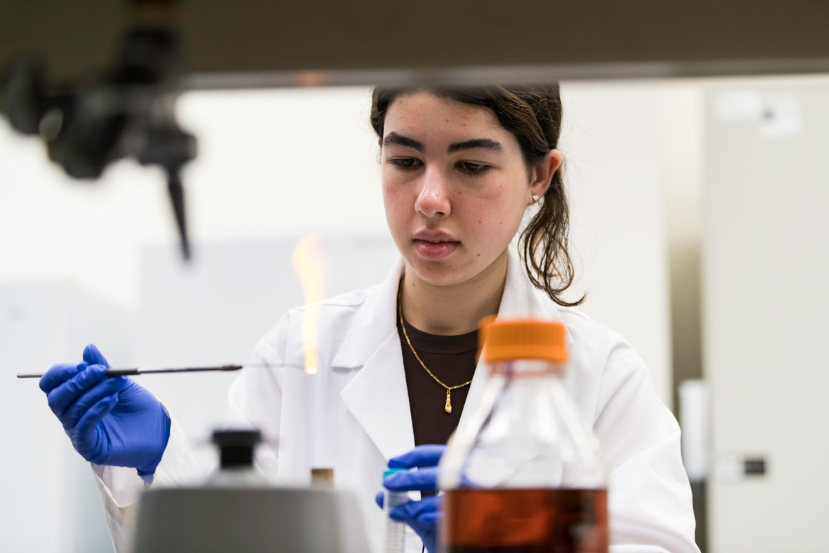A female scientist in a lab coat conducts research in a University of Rochester laboratory.