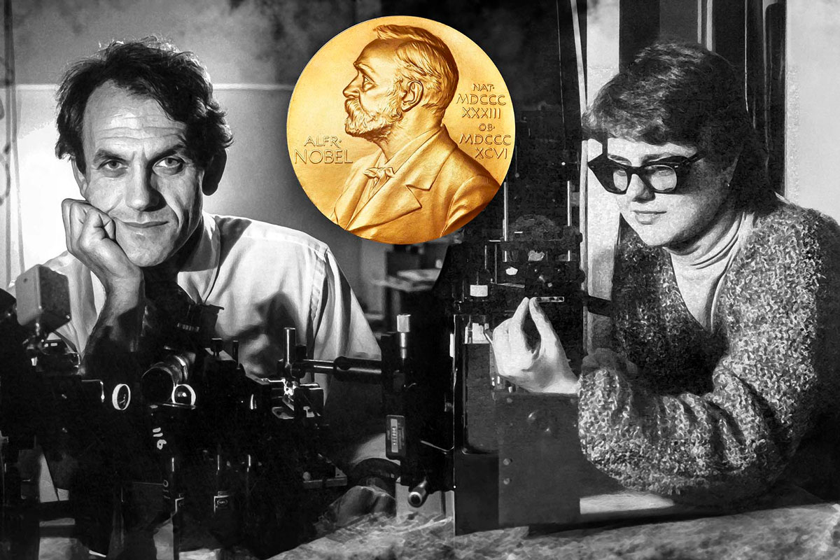 Two people in glasses examine a gold medal at the University of Rochester’s Laboratory for Laser Energetics.