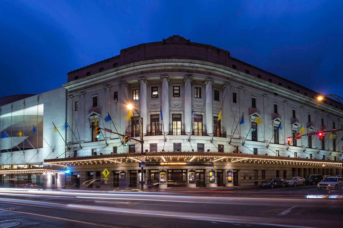 A large building illuminated at night, representing the University of Rochester's Eastman School of Music.