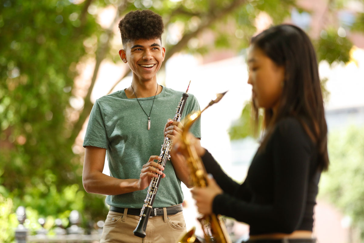 A young man and woman play saxophones together at the University of Rochester, showcasing their musical talent and collaboration.