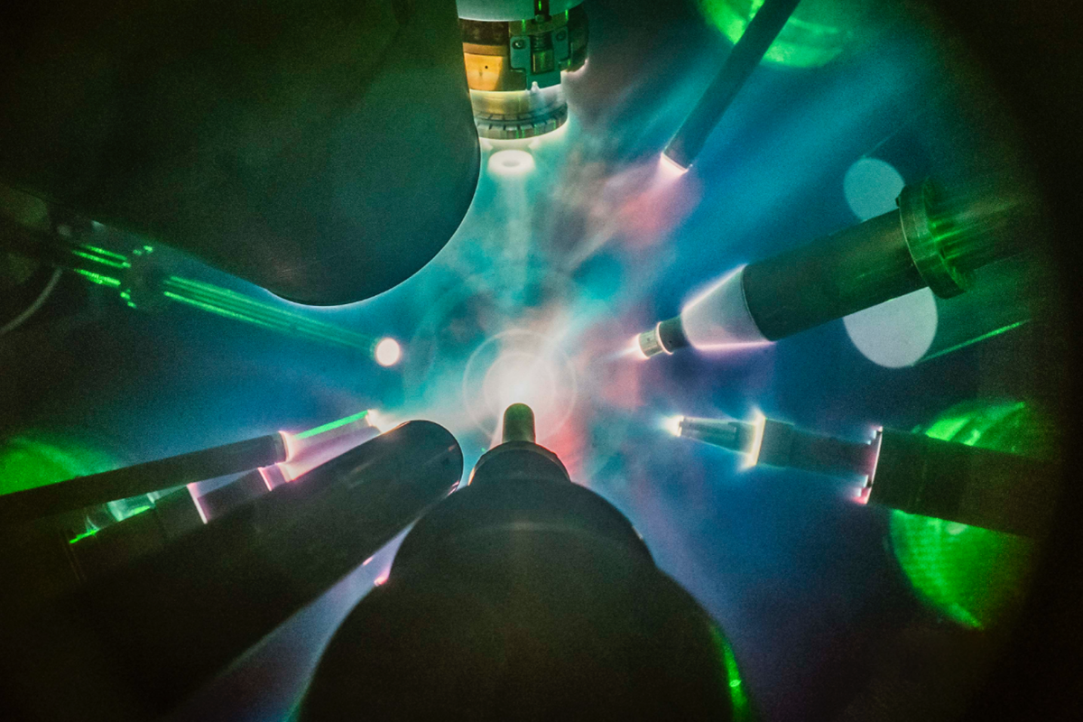 Scientific instruments illuminated by a green light, set against the backdrop of the University of Rochester’s Laboratory for Laser Energetics.