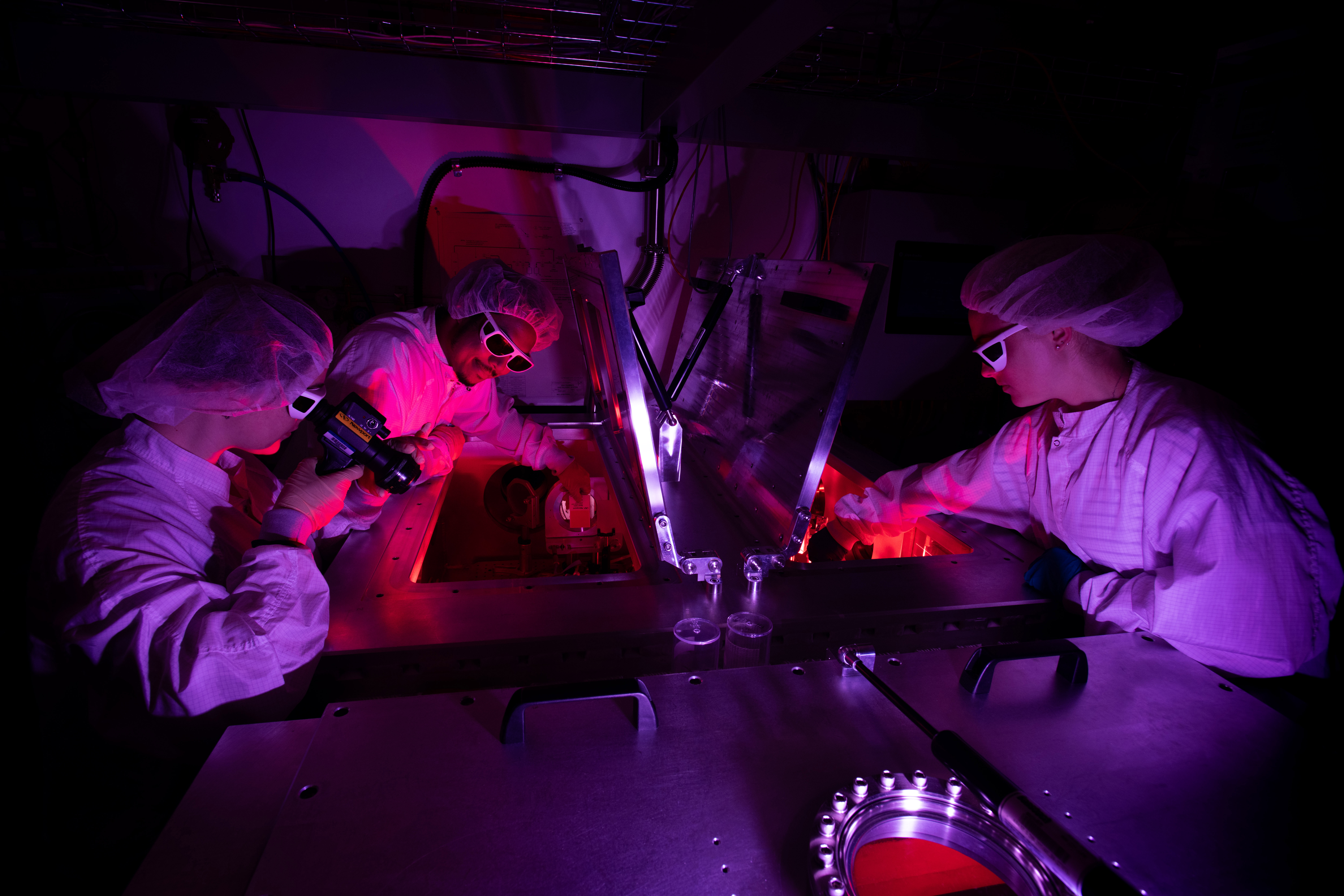 A woman in a white lab coat stands in the University of Rochester’s Laboratory for Laser Energetics.