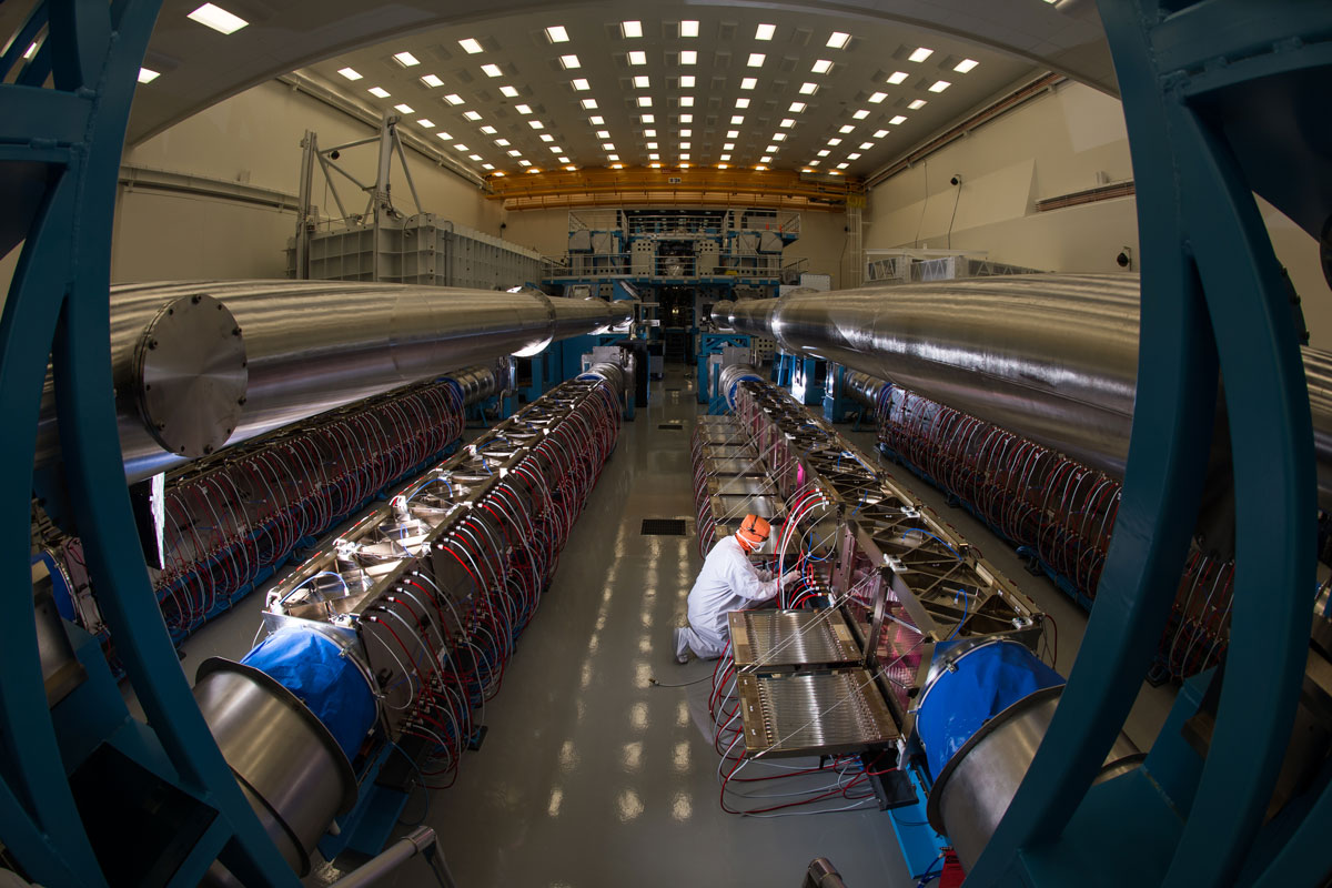 A man operates a machine in the expansive University of Rochester Laser Lab, showcasing advanced technology in action.