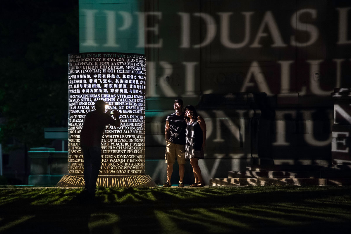 A man and woman stand before a large illuminated sculpture at the University of Rochester Memorial Art Gallery.