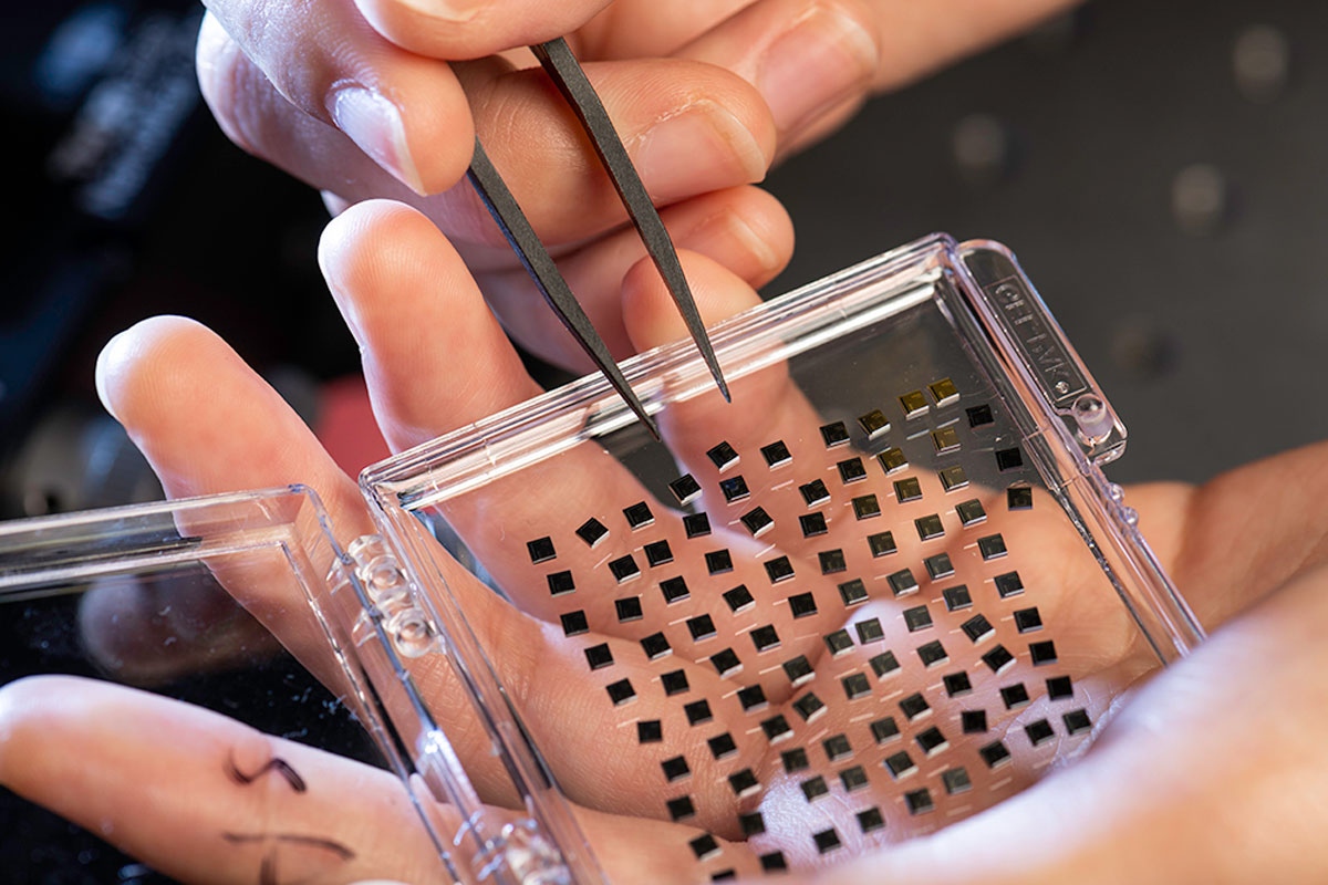 A researcher at the University of Rochester cuts a piece of plastic with scissors during a project.