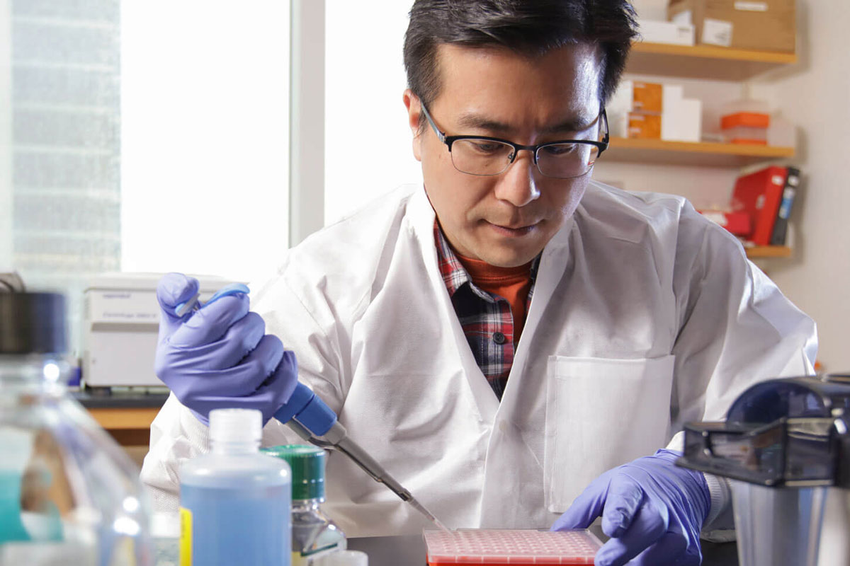 A researcher in a lab coat conducts experiments for a University of Rochester project.