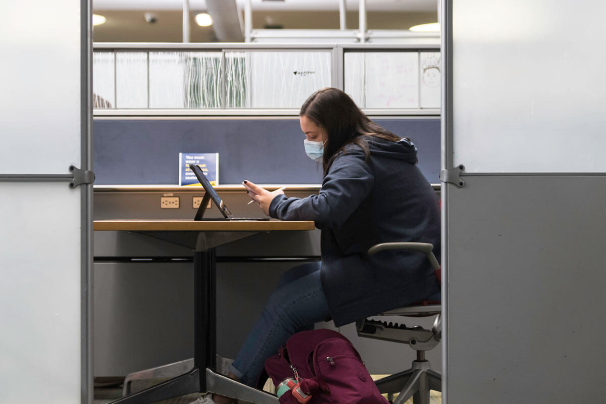 University of Rochester undergraduate student in the library looking at their phone.