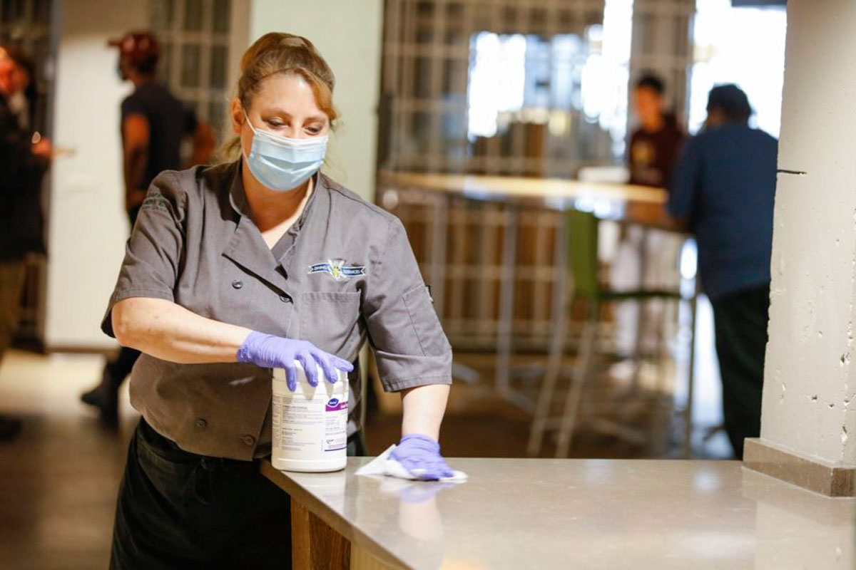 University of Rochester dining services worker cleaning a shared surface using sanitary wipes.