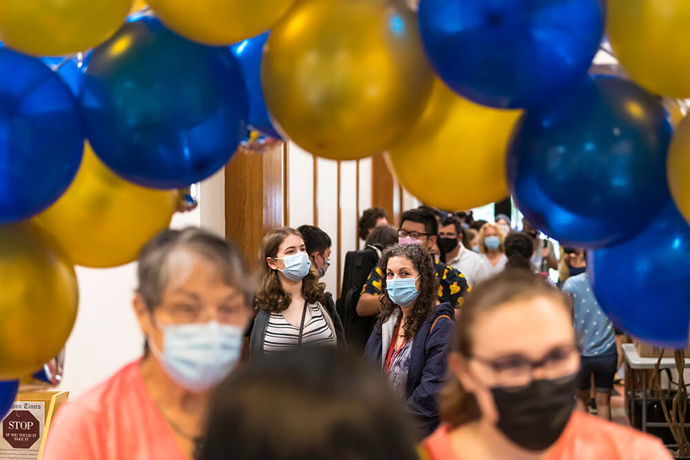 student and her mother standing beneath an arch of blue and yellow balloons