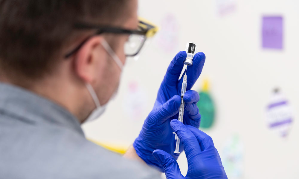 Pharmacy worker prepares doses of the COVID-19 vaccine into a syringe.