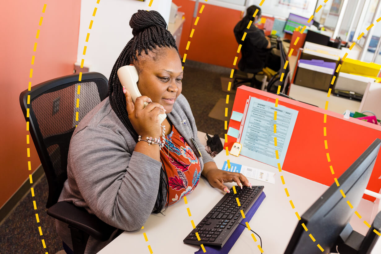 University of Rochester staff memeber answers a phone while seated at a desk.