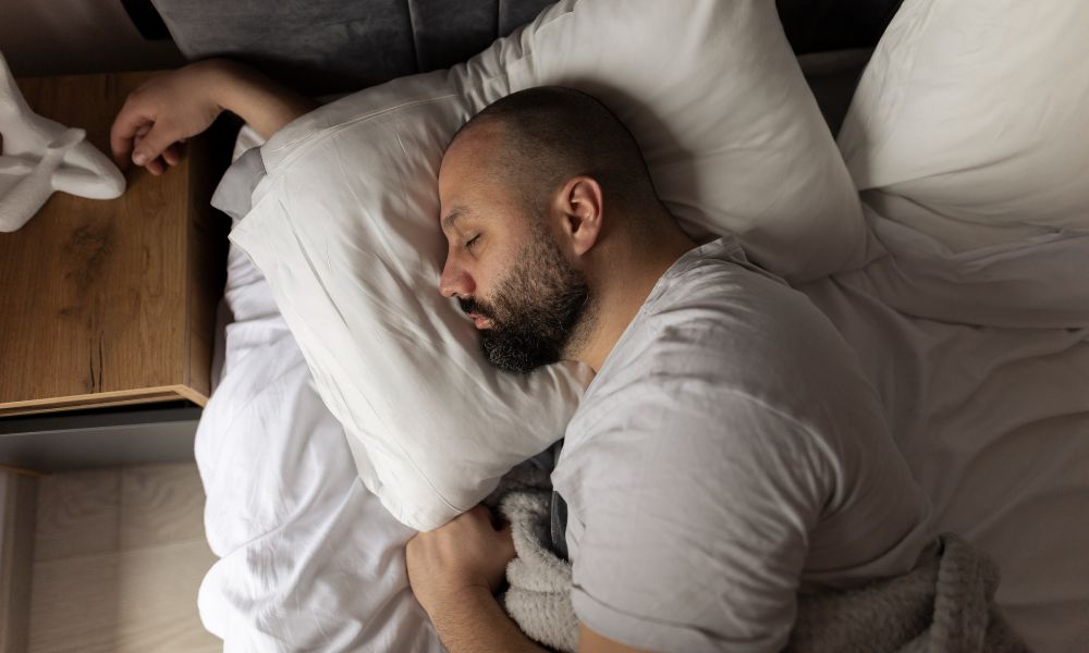 A man peacefully sleeping in bed, resting his head on a soft pillow.