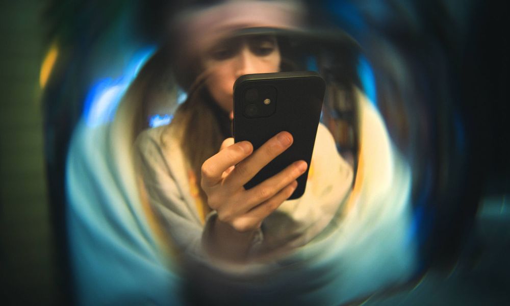 Young woman deeply engaged with her smartphone, seen through a distorted, swirling blur effect to illustrate the concept of social media echo chambers.