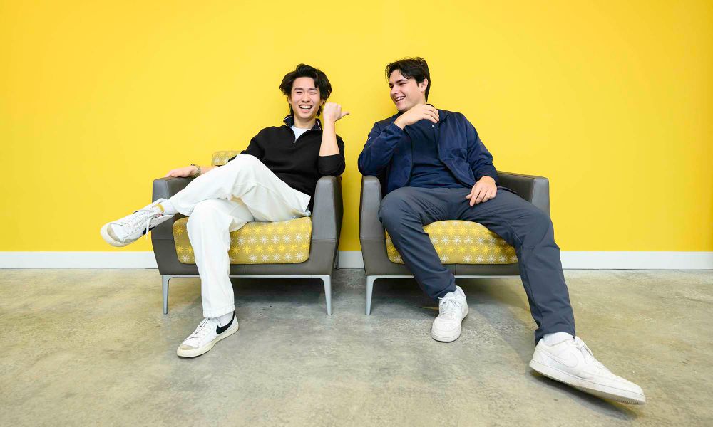 Steve Lim and Walter McDonald smile while seated in chairs against a bright yellow background.