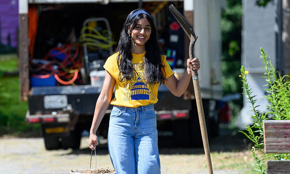 A University of Rochester student carries a bucket and shovel while smiling during a community service activity that helped result in the Carnegie Community Engagement Classification for the institution.