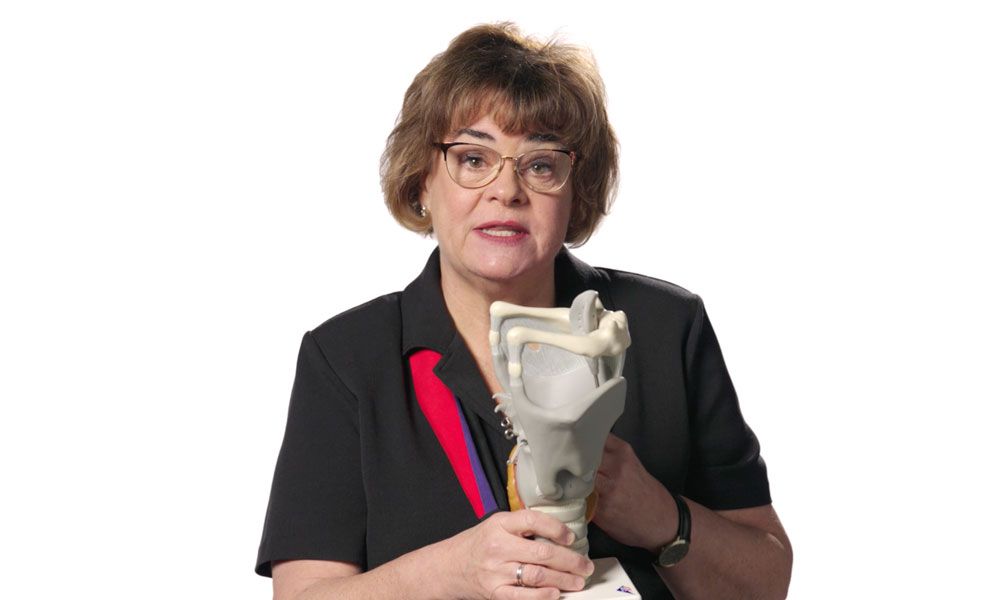 Kathryn Cowdrick, a mezzo soprano opera singer, holds a small object while wearing glasses, showcasing her artistic presence.