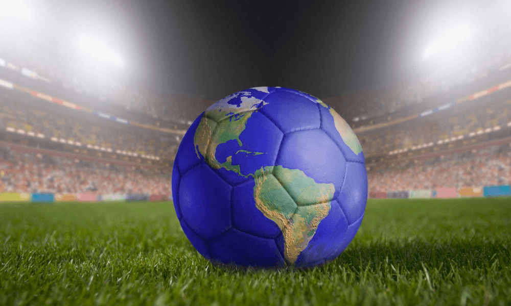 A soccer ball made to look like the earth sits on an empty soccer field