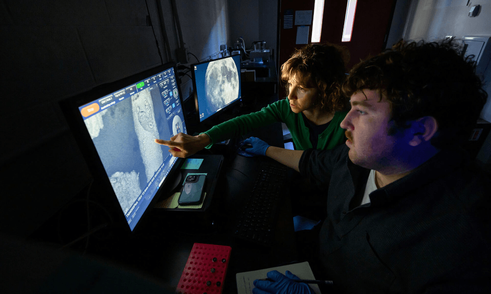 Paleoceanographer Chiara Borrelli and graduate student Adrien Trendell in a darkened room examine high-resolution images of foraminifera microfossils.