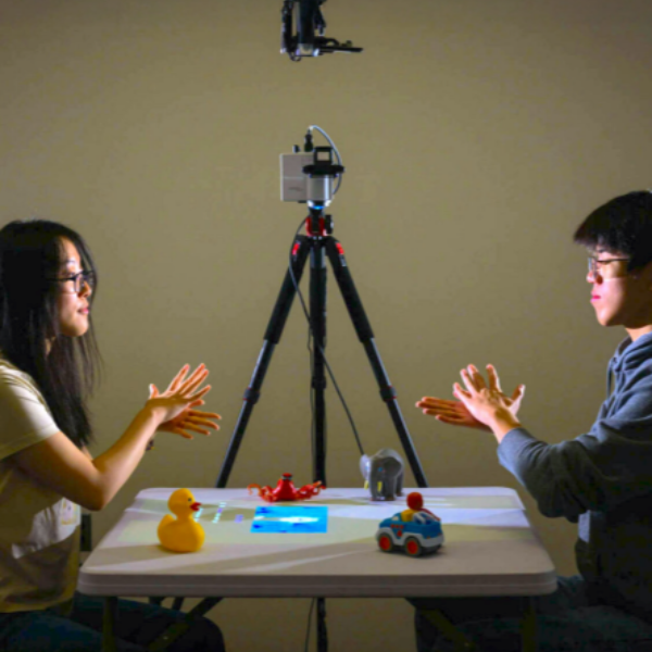 Two people seated at a table with a camera and tripod, engaged in discussion at the University of Rochester.