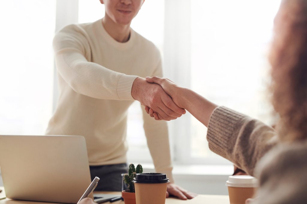 Two people shake hands over a desk