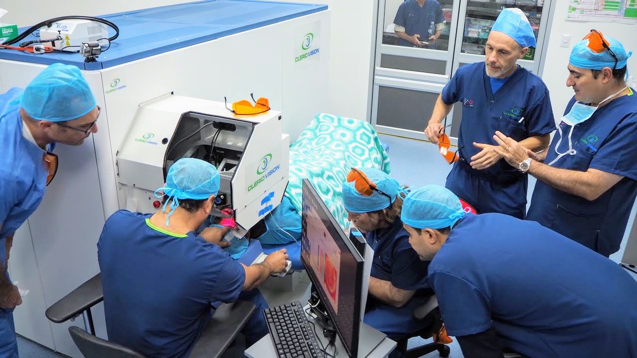 Several people in blue scrubs with blue hairnets working on computer equipment for Clerio Vision