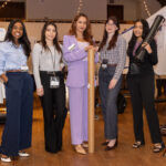 Five women pose in front of their research posters during the poster session.