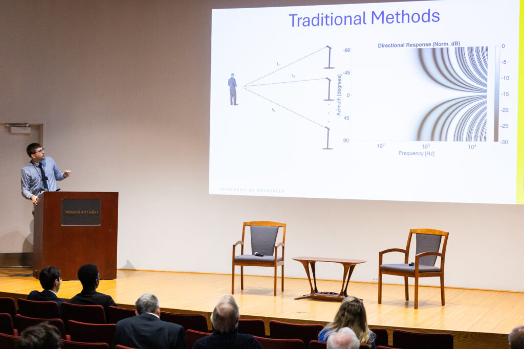 Michael Heilemann at the podium explaining a slide projected on the wall entitled "Traditional Methods" with a graphical illustration, during the Networking Pitch Session