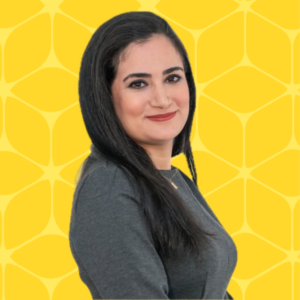 headshot of Maryame Kouram who is smiling and posing to the side with a yellow box designed background